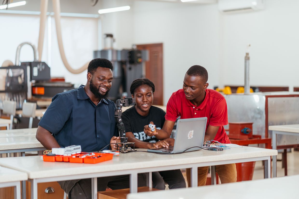 Three students work together on a laptop