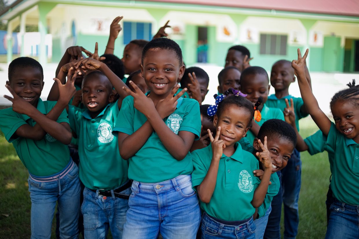 Un groupe d'enfants fait le signe de la paix à la caméra