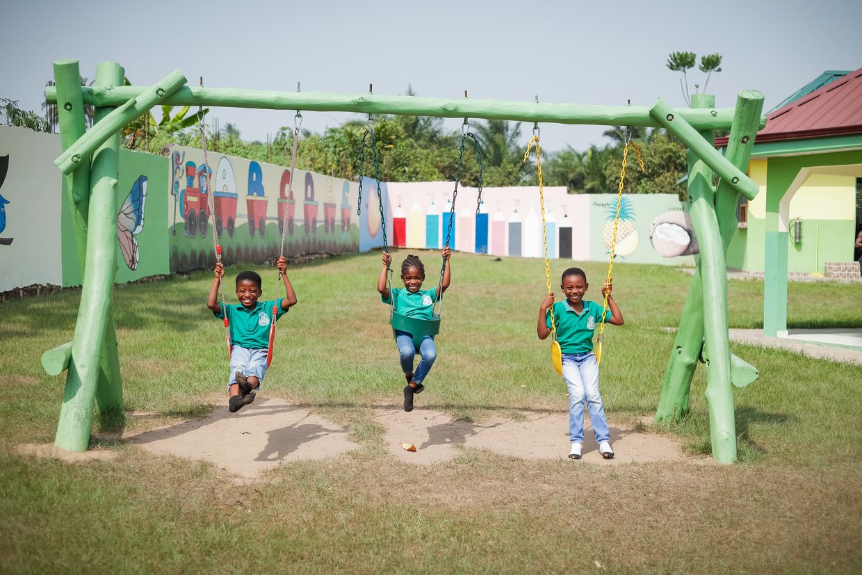 Enfants se balançant dans la crèche Montessori de l'usine ghanéenne de fruits secs de HPW