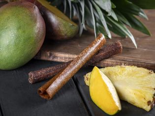 Composition de rouleaux de fruits secs entourés d'ananas et de mangues frais.